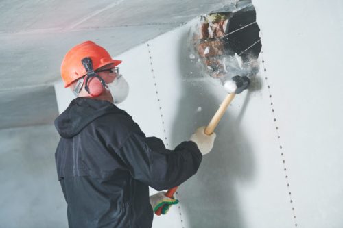 person performing demolition services to a wall